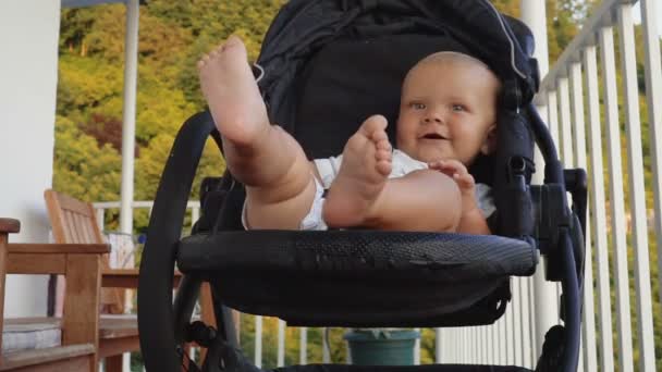 Baby jongetje glimlachend en zwaaiend in de wandelwagen. Jeugd dromen en herinneringen. — Stockvideo