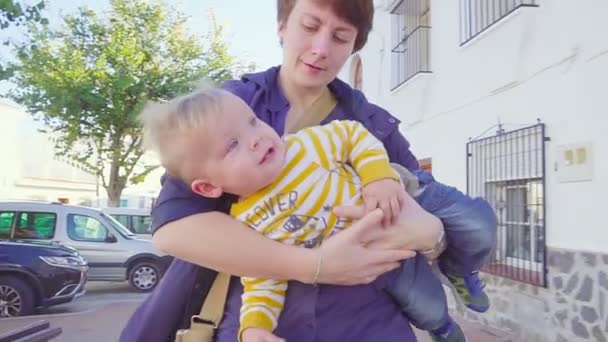 Mom Carries Her Little Boy, He looks to the Camera — Stock Video