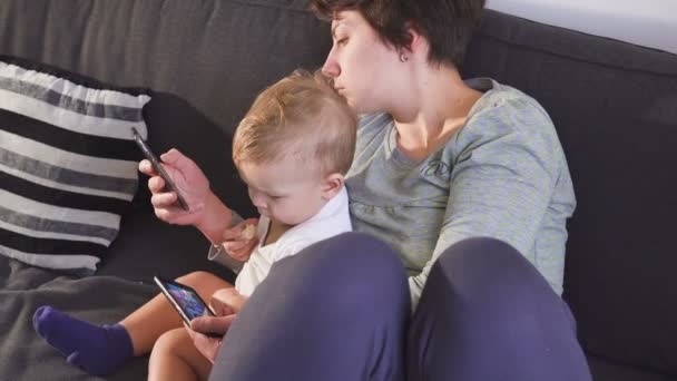 Moeder en zoon zoekt op hun smartphones. Gadget verslaving concept. — Stockvideo