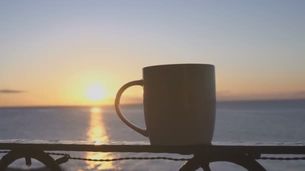 Female hand takes cup of coffee near sea at sunny morning — Stock Video
