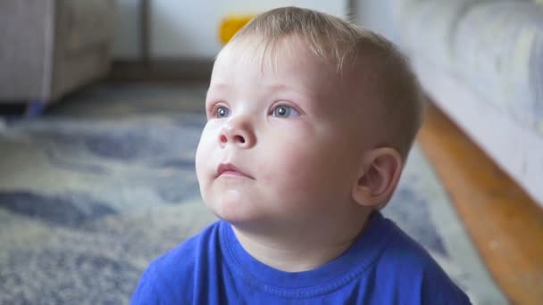 One year old child watching TV - dolly shot. Little boy watching cartoon on tv in the room. — Stock Video