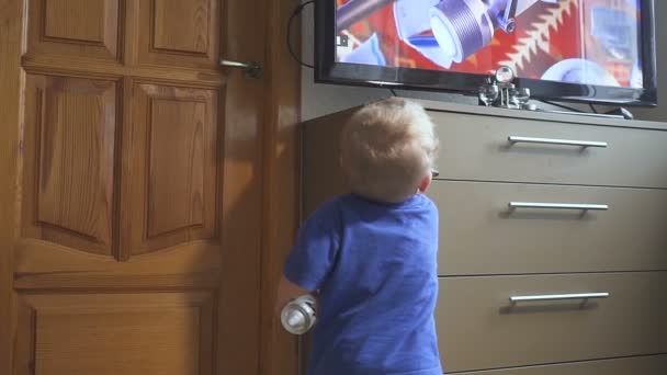 Un año de edad, niño viendo la televisión - dolly shot. Niño viendo dibujos animados en la televisión en la habitación . — Vídeo de stock