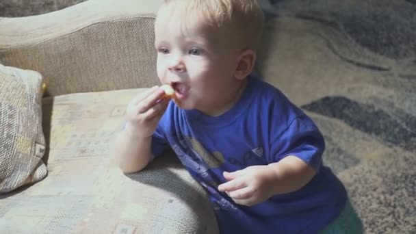 Einjähriges Kind vor dem Fernseher - Frontalzusammenstoß. kleiner Junge schaut Zeichentrickfilm im Fernsehen im Zimmer und isst. — Stockvideo