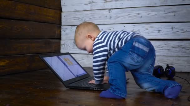 Das schöne einjährige Kind wird mit einem Laptop gespielt. Geschäftliches Konzept — Stockvideo