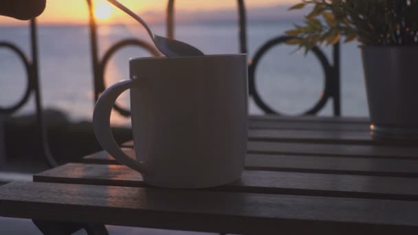 Joven toma taza de café cerca del mar en la mañana soleada — Vídeos de Stock