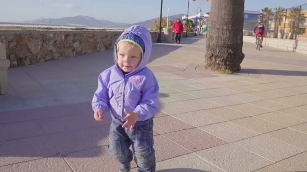 Babyjongen loopt langs de stoep in de buurt van de zee — Stockvideo