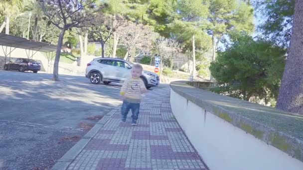 Сонячне літо. Стейдікам постріл хлопчика, що біжить по тротуару, повільний рух — стокове відео