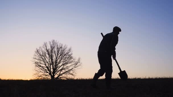 Het silhouet van de werknemers shoveling de bodem met een spade in de avond. — Stockvideo