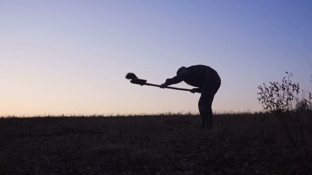 La silhouette dei lavoratori che spalano il terreno con una vanga la sera . — Video Stock