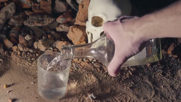 Man pours alcohol and drinks on the background of the skull. alcohol addiction cincept. 4k — Stock Video