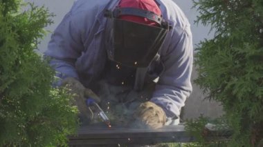 Kaynakçı Metal kaynak ile kıvılcım ve özel bir bahçede sigara içmek.
