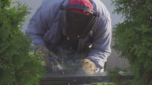 Welder of Metal Welding with sparks and smoke in a private garden. — Stock Video