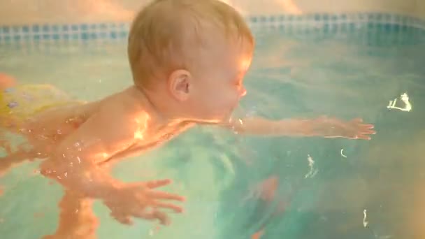 Uma jovem mãe com um menino nada e se diverte na piscina. Menino feliz está nadando na piscina junto com sua mãe — Vídeo de Stock