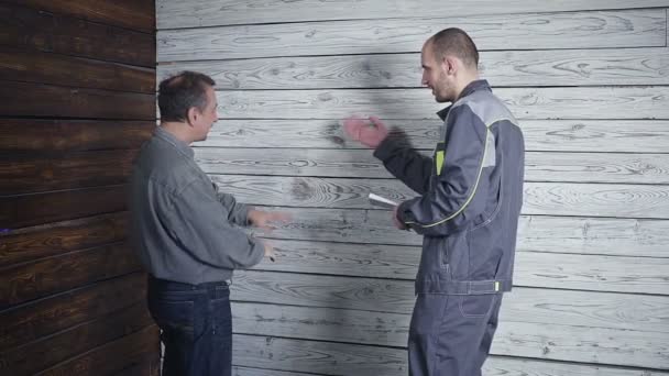 Trabajador y el cliente exigente para discutir y jurar sobre el fondo de una pared de madera. Problema en la construcción . — Vídeos de Stock