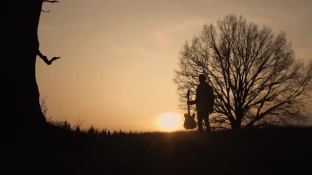 Gitarist günbatımı yavaş hareket, silüeti. Onun elinde gitar gitarist yürür — Stok video