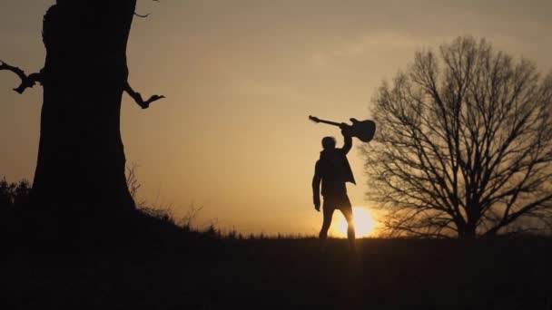 Silhouette del chitarrista al tramonto slow motion. Il chitarrista agita la mano — Video Stock