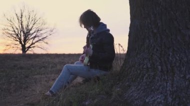adam elektro gitar çalış ve gün batımında ağaç bir tarlada olarak lirik bir şarkı söyler