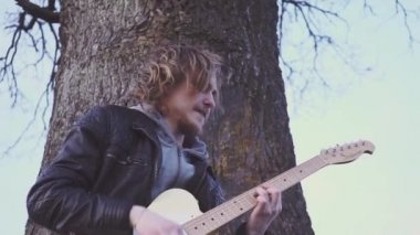 adam elektro gitar çalış ve gün batımında ağaç bir tarlada olarak lirik bir şarkı söyler