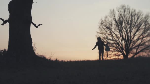 Silhouette of guitarist at sunset slow motion. runs with a guitar in his hands — Stock Video