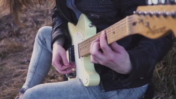 Mężczyzna gra gitara elektryczna w polu w pobliżu drzewa o zachodzie słońca. zwolnionym tempie — Wideo stockowe