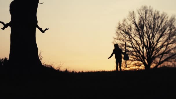 Silhouette of guitarist at sunset slow motion. runs with a guitar in his hands — Stock Video