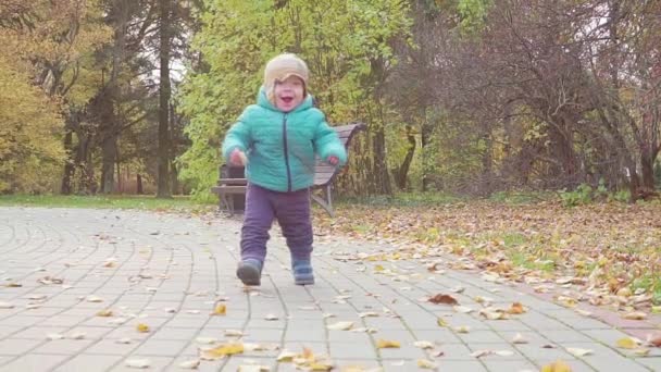 Rolig leende 1 år gamla pojke promenader i parken vid solnedgången med bröd i handen. Lycklig barndom koncept. Slow motion — Stockvideo