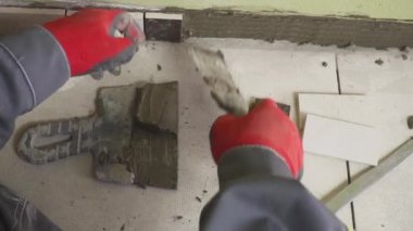 Çalışan küçük fayans mutfak duvar ayarlar. Elleri döşeme üzerinde yapışkan yerleştirir. çekim stedikam