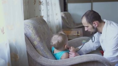 Doktor hastanın bebek evde ziyaret etti. Bebek stetoskop ile