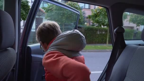 Grundschüler gehen zur Schule. der Junge steigt aus dem Auto und winkt seinen Eltern zu — Stockvideo