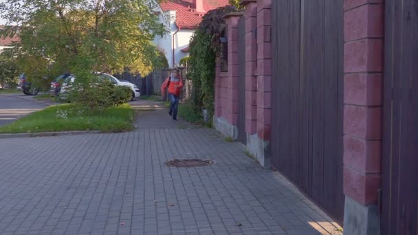 A ten year old student runs to, from the school with a backpack on his back and smiles. Slow motion — Stock Video