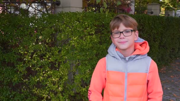 Retrato de un colegial que de pie, sonriendo y mirando a la cámara. El final del verano, el comienzo del otoño — Vídeo de stock