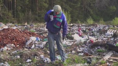 sırt çantalı bir çöplükte evsiz bir adam portresi. Çantada boş şişe olduğunu.