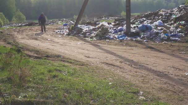 Hajléktalan férfi sétált a szemétdomb lerakó. Éhezés és a szegénység — Stock videók