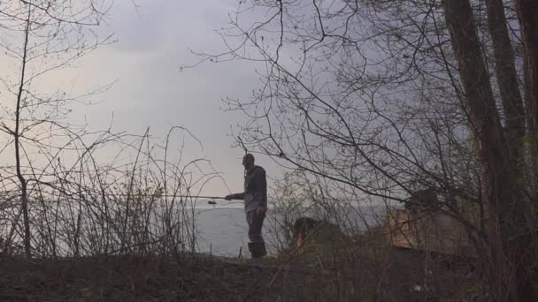 Pescador en un viaje de pesca en un lago con una caña de pescar en la mano — Vídeos de Stock