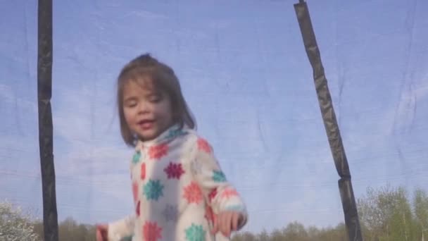 Feliz niña de tres años saltando en un trampolín. Retrato emocionalmente alegre. Movimiento lento — Vídeo de stock