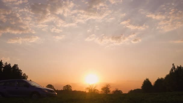 Silhueta de um carro em um campo no pôr-do-sol. A estrada e o campo. O carro no campo . — Vídeo de Stock