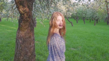 bahar çiçekleri beyaz bir elma bahçesi içinde yürüyen genç kadın cazip. Akşam meyve bahçesinde bir güzel kız portresi.