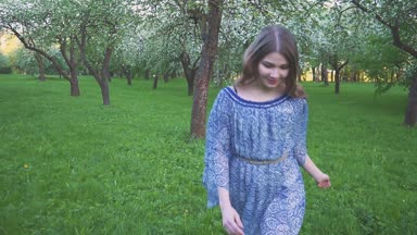 Genç kadın bir elma bahçesi bahar çiçekleri beyaz içinde çalışır. Akşam meyve bahçesinde bir güzel kız portresi.