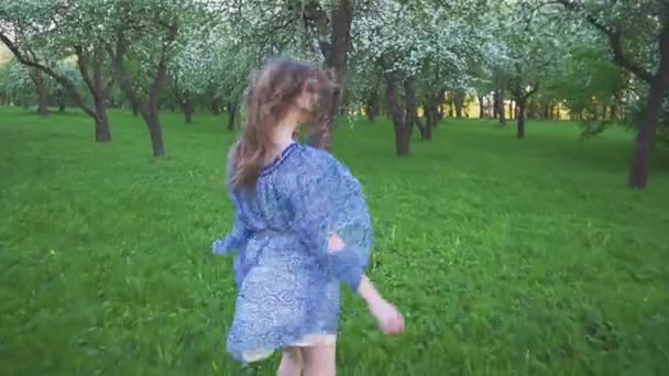 Mujer joven corre en un huerto de manzanas en las flores de primavera blanco. Retrato de una hermosa niña en el jardín de frutas de la noche . — Vídeos de Stock