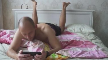 Genç Yakışıklı Adam Yatakta Akıllı Telefon Kullanıyor.