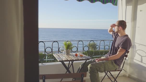 Счастливый молодой человек отдыхает на роскошной террасе отеля — стоковое видео