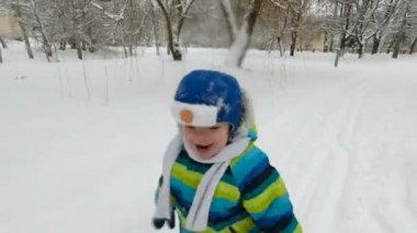Mutlu küçük çocuk kışın parkta koşar. Kar parkında eğlenen mutlu çocuk. Gülümsüyor. yumuşak odak