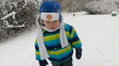 Mutlu küçük çocuk kışın parkta koşar. Kar parkında eğlenen mutlu çocuk. Gülümsüyor. yumuşak odak