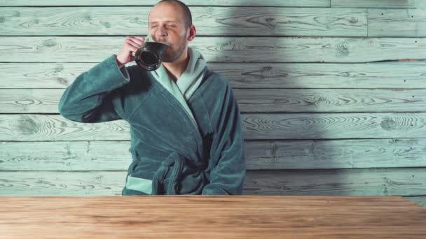 Cerveja e Sauna. Banheira e spa. Bonito homem de roupão está bebendo cerveja e dizendo brinde . — Vídeo de Stock