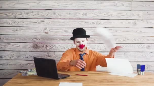 Clownaffärsman leker med kontorsdokument. Kasta dem på marken och de faller. — Stockvideo