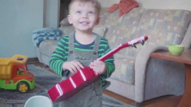 Fröhlicher kleiner Junge spielt Gitarre, singt und tanzt — Stockvideo