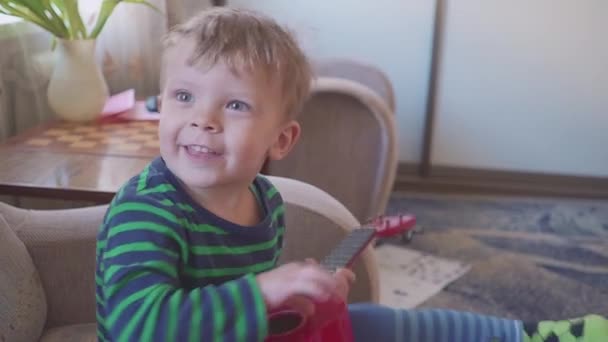 Cheerful little boy is playing guitar singing and dancing — Stock Video