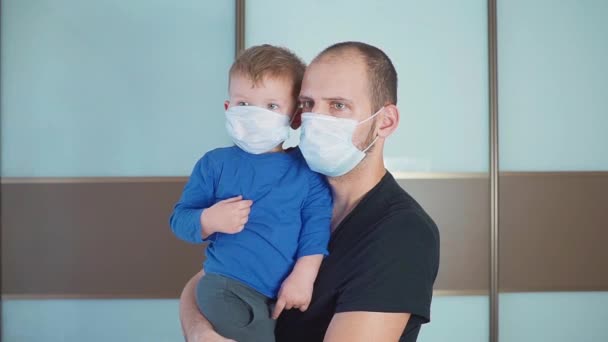 Πορτρέτο του Πατέρα κρατώντας χαριτωμένο μικρό παιδί αγοράκι φορώντας προστατευτική ιατρική μάσκα — Αρχείο Βίντεο