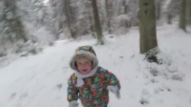 Το χαρούμενο αγόρι τρέχει σε ένα χιονισμένο χειμερινό δάσος. Είναι ευτυχισμένος — Αρχείο Βίντεο