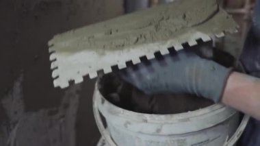 İnşaat işçisinin eli inşaat alanında beton sıva kullanarak duvar ve kiriş yapıştırıyor.